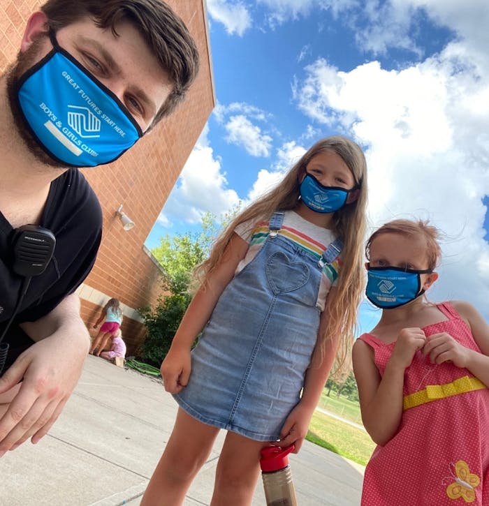 Boys & Girls Clubs staff member with two students, wearing branded face masks